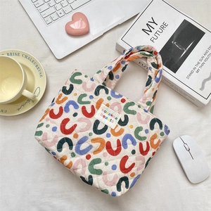 Détail du sac fourre-tout matelassé avec motifs colorés et étiquette sozakka sur bureau