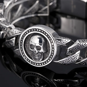 Macro shot of silver stainless steel skull bracelet featuring Greek fret pattern details