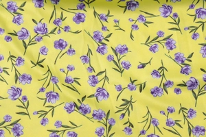 Macro detail of summer dress fabric showing purple floral print on yellow polyester