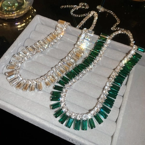 Macro shot of rectangular emerald and diamond tassel necklaces on velvet tray