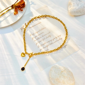 Gold OT clasp chunky chain necklace with heart and black gemstone pendants on a desk