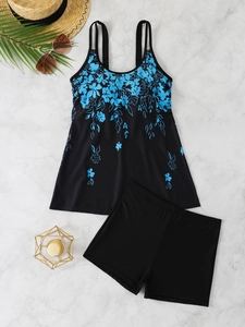 Detailed flat lay of black tankini swimwear with blue floral print and beach accessories