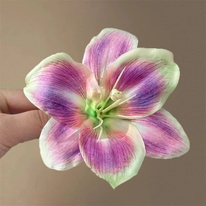 Realistic purple lily hair clip with green gradient petals held by hand for seaside vacation