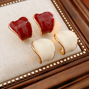 Dettaglio degli orecchini a C smaltati placcati in oro nei colori rosso scuro e beige