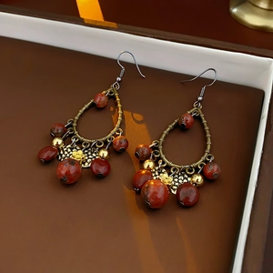 Detailed close-up of retro bohemian earrings with teardrop metal frame and red beads