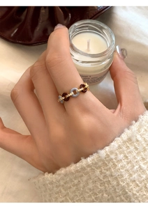 Close-up of interlocking zircon rings worn on finger while holding a scented candle