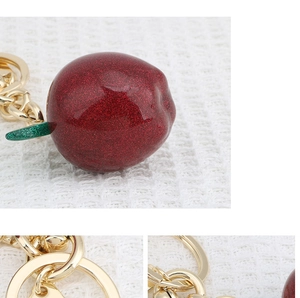 Detail of red glitter apple keychain with golden metal ring and green leaf stem