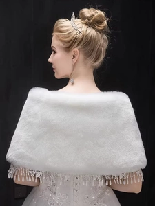 Detail of bridal white faux fur shawl with delicate lace trim and hanging pearl tassels