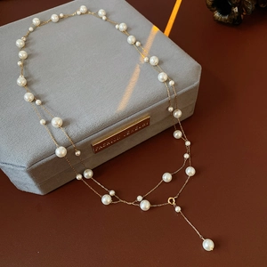Detail of vintage layered pearl necklace with gold chain on a velvet jewelry box