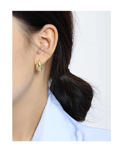 Detailed macro view of gold-tone teardrop stud earrings with a glossy mirror finish