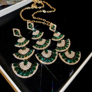 Detail of vintage gold fan necklace and earrings set with emerald green water drop gems