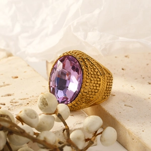Detail of a vintage gold ring with purple oval gemstone and textured hammered metal band