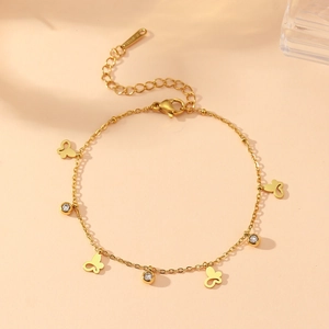 Détail du bracelet papillon doré avec pendentifs en zircone et étiquette en acier S.STEEL