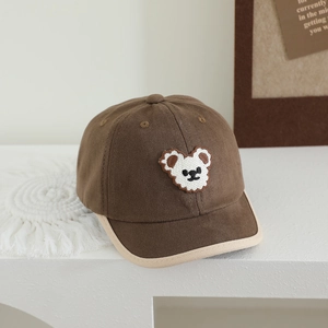 Detailed view of kids brown baseball cap with embroidered bear and beige contrast piping