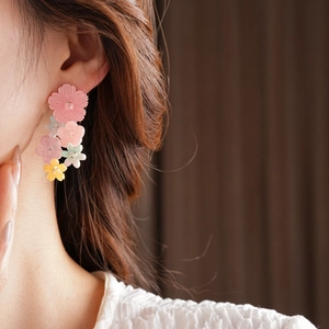 Detail of long floral tassel earrings with pink resin petals and silver needle studs