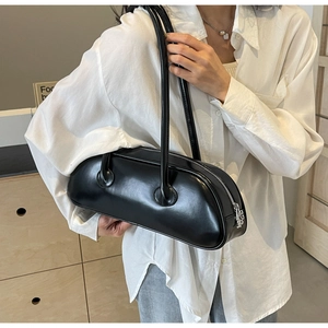 Detail of a large black underarm bag with silver zipper on a model wearing a white shirt