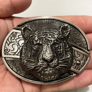 Close-up of a silver metal tiger head belt buckle with 3D relief and vintage texture