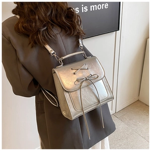 Detail of silver metallic backpack with decorative lace-up bow and polished finish