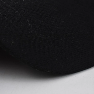 Close-up of black baseball cap visor featuring detailed twill fabric and curved stitching