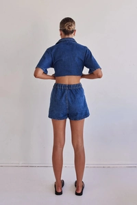 Back view of a dark blue denim set showing cropped shirt and elastic waist shorts