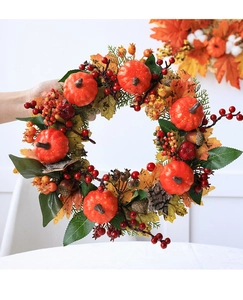 Detail of autumn wreath with orange pumpkins, pine cones, berries, and maple leaves