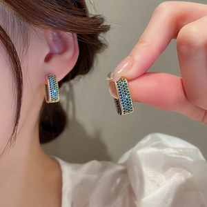 Detailed close-up of gold rectangular earrings with blue and green gradient crystals