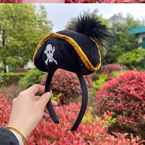 Detail of pirate hat headband with black feathers, gold trim, and skull print