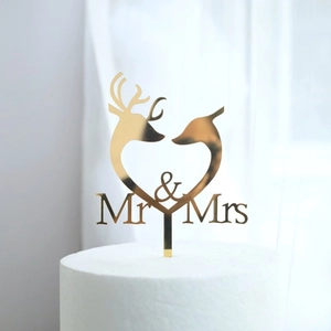 Close-up of golden Mr & Mrs cake topper with deer silhouettes in a heart frame