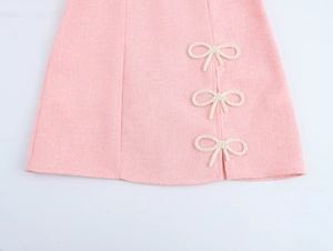 Detail of pink tweed dress showing side slit and three elegant pearl bow decorations