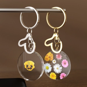 Nahaufnahme von handgefertigten Acryl-Schlüsselanhängern mit Trockenblumen in Gold und Silber