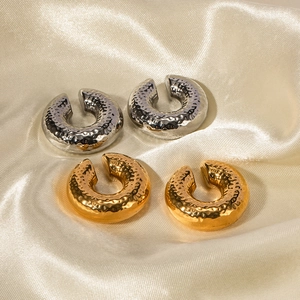 Textured C-shape cuff earrings in gold and silver steel on yellow silk background
