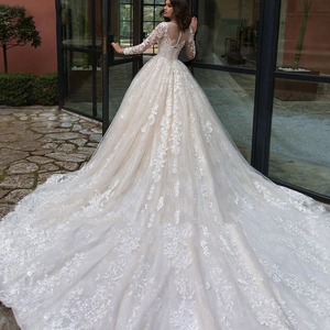 Elegant white long-sleeve lace wedding dress with a long train and intricate floral embroidery