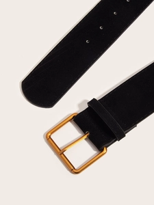Detail of black suede belt with a polished gold square buckle on a beige background