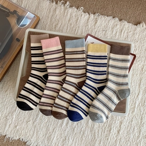 Flat lay of five pairs of colorful striped cotton mid-tube socks in a white tray