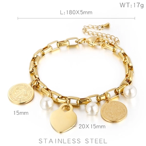 Détail d'un bracelet en acier doré avec des charms cœur, perle et médaille de saint