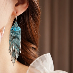 Macro close-up of blue rhinestone tassel earrings on a model with blurred background