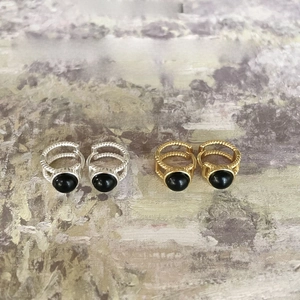 Retro twisted silver and gold hoop earrings with black agate stones on artistic background