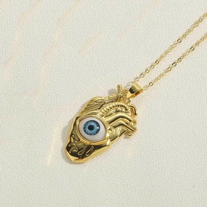Detailed close-up of a golden anatomical heart pendant with a realistic blue evil eye