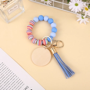 Detail of beaded silicone wristlet with wooden disc, blue tassel and gold clasp