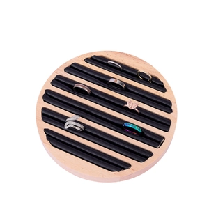 Detail of round solid wood ring display tray with black velvet slots and several rings