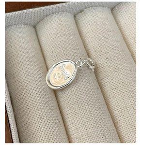Macro shot of silver oval pendant with Smile engraving in a beige jewelry box
