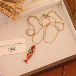 Detail of red koi fish pendant with colorful gems on a golden snake bone chain necklace