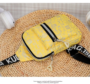 Detailed top view of yellow nylon crossbody bag with heart prints on a woven mat