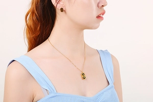Detailed view of model wearing gold paperclip chain necklace and black rectangle studs