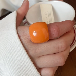 Close-up of a large orange square resin ring on a hand with minimalist aesthetic
