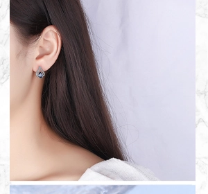 Detailed close-up of a blue teardrop-shaped crystal earring worn by a female model