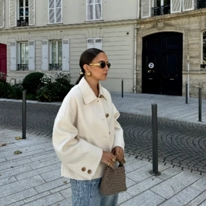 Detail of cream oversized wool jacket featuring large lapels and buttoned cuffs style