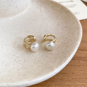 Detail view of gold double-layered irregular pearl ear cuff on a ceramic plate