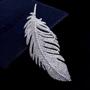 Close-up of a silver feather brooch with sparkling zircons on a dark velvet jewelry box