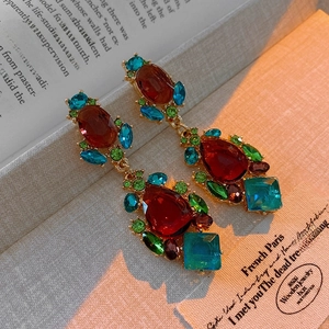 Macro shot of vintage court style teardrop earrings with colorful crystals on book
